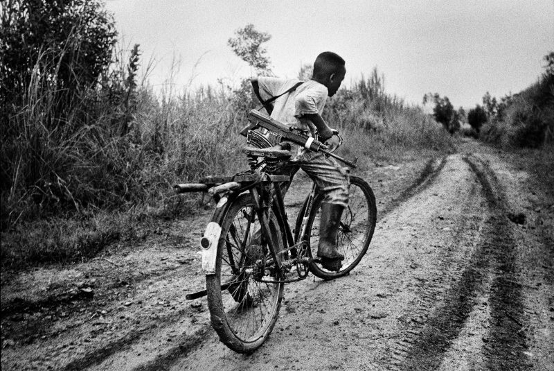 A child soldier rides back to his base in Ituri district, northeastern Congo. 2003