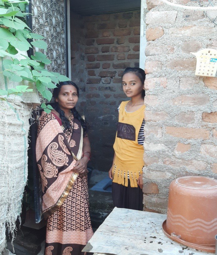 Darshana and her daughter pose outside their new bathroom at home.