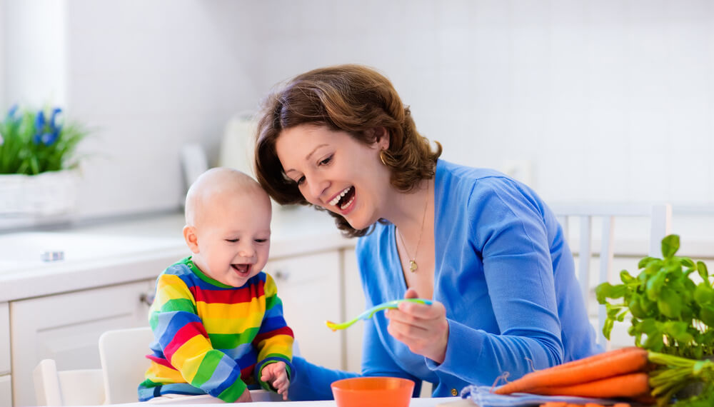 Mother feeding baby with carrots
