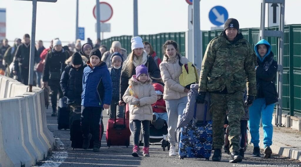 In the Photo: Ukrainian refugees from March 2022, crossing into Poland
Photo Credit: Wikimedia Commons