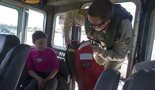A Border Patrol Riverine Unit rescues a child who is stranded on the river bank of the Rio Grande. A Border Patrol agent provides a life vest to ensure the child's safety on the boat. Photographer: Donna Burton