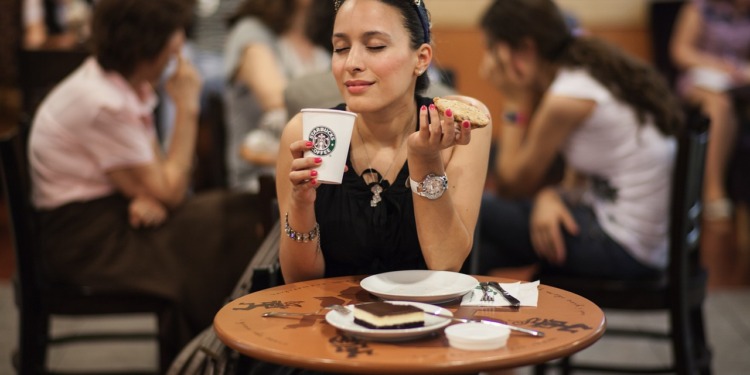 A woman drinking from a Starbucks cup.