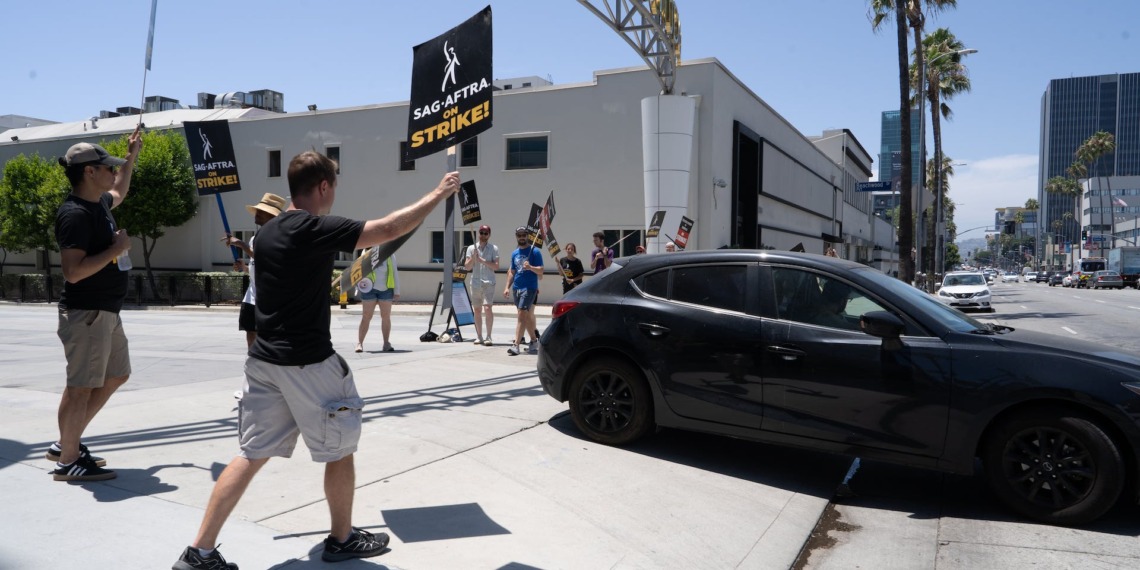 SAG-AFTRA union members on strike, walking down a road.