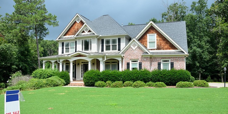 Home ownership: a beautiful country home with sales sign