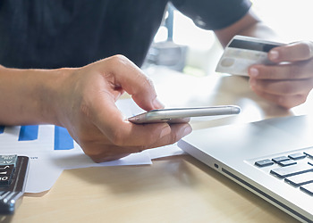 A man holding a phone and choosing which payments orchestration platform he should be using.