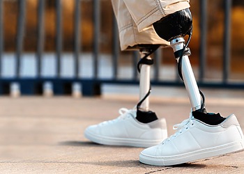 View of a walking man with prosthetic legs and white sneakers frimufilms