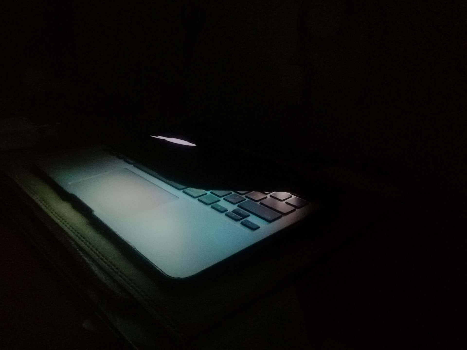 The glow of a half closed laptop in a dark room