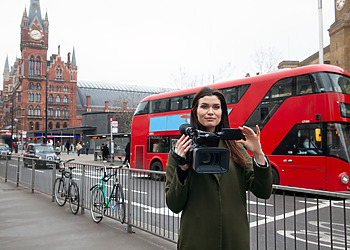 Content production in London - Woman standing with a camera in front of Westminster.