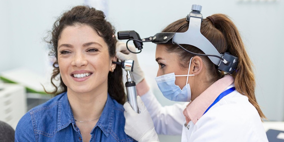 A doctor performing ENT care and assistant on female patient.