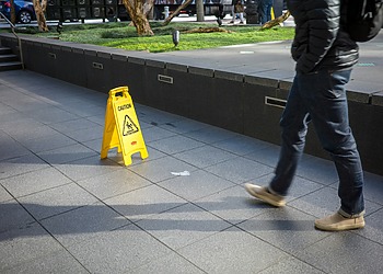 A man walks toward a yellow caution sign to prevent slip and fall accidents