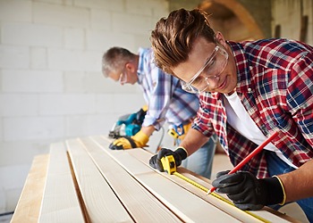 Home deck repair crew in action with two men working at each end of a wooden planks