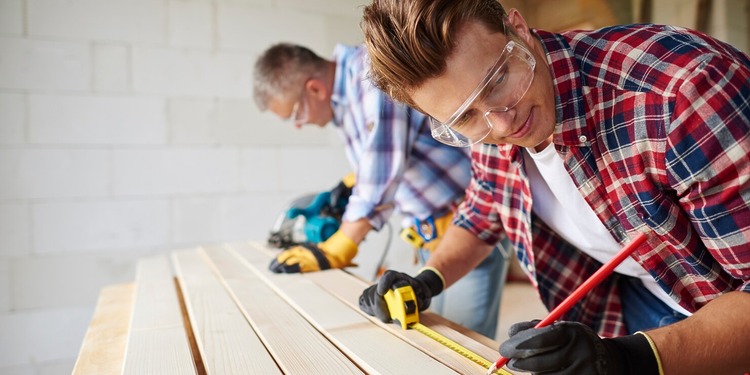Home deck repair crew in action with two men working at each end of a wooden planks