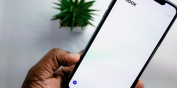 Man holding a iphone showing an white screen with written Inbox