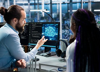 A woman and a man from the IT team working with the support of an AI agent.
