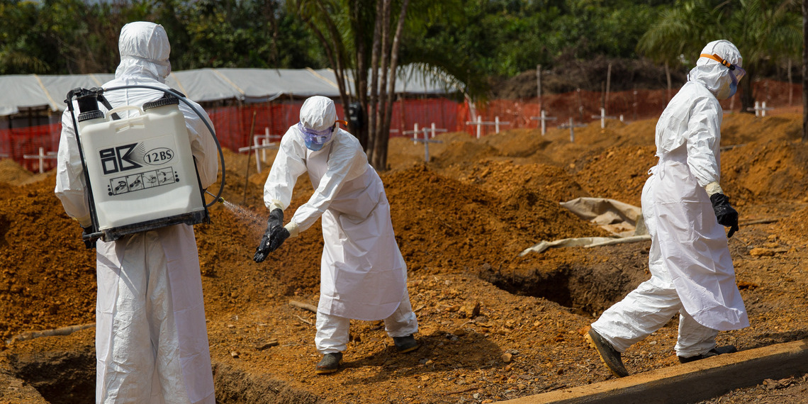 Members of a burial team disinfect each other after they carried the body of a suspected Ebola victim in a new cemetery.