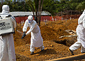 Members of a burial team disinfect each other after they carried the body of a suspected Ebola victim in a new cemetery.