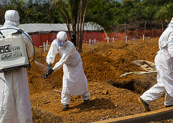Members of a burial team disinfect each other after they carried the body of a suspected Ebola victim in a new cemetery.