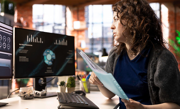 Woman engineer at her desk with pc screens turned on.