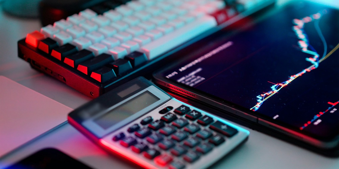 A laptop computer sitting on top of a desk next to a calculator