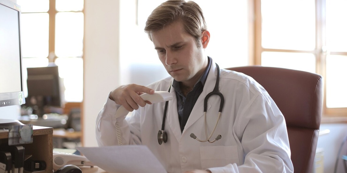 Young physician working in a medical office, representing the financial and career challenges facing doctors entering the healthcare workforce.