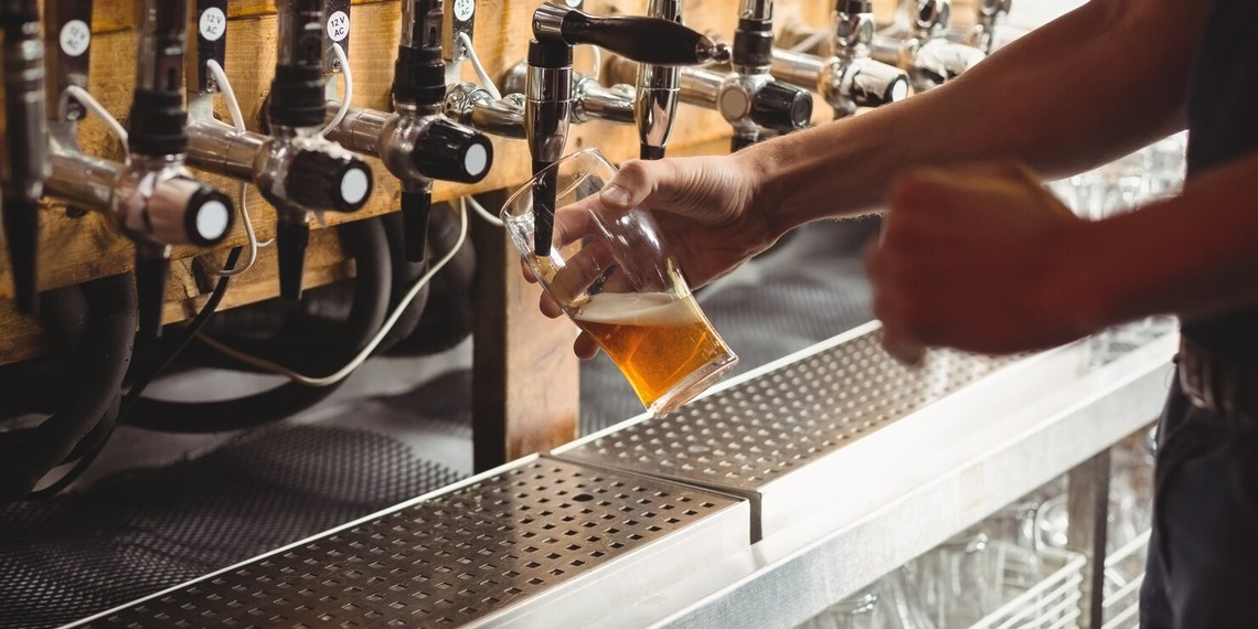 Bartender pouring draft beer from a commercial tap system designed to maintain beverage quality and consistency.