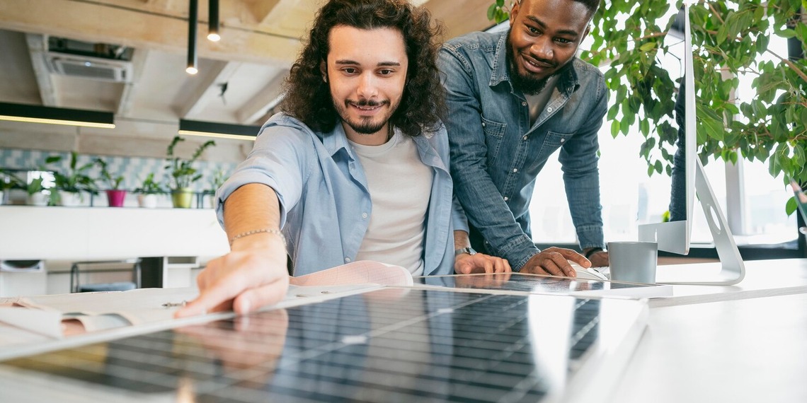 Two people inspecting a community solar panel installation that helps households lower electricity costs through shared renewable energy.