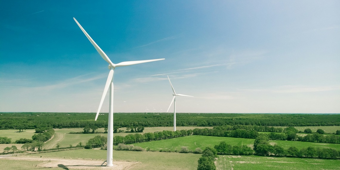 A shot of two wind turbines in a field in rural France