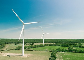 A shot of two wind turbines in a field in rural France