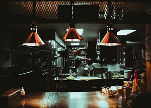 woman standing near three red pendant lamps in dark kitchen