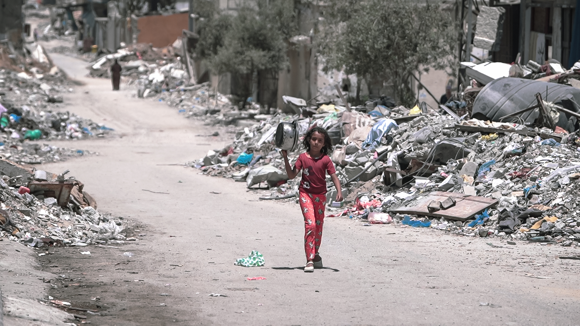Girl walks in Gaza during the Gaza–Israel war with a pot to get food.