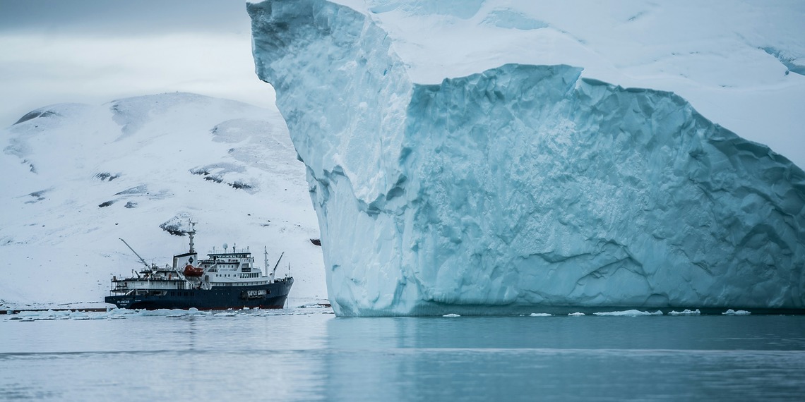 Ship sailing near an iceberg in Arctic waters