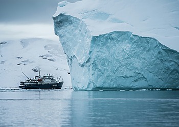 Ship sailing near an iceberg in Arctic waters