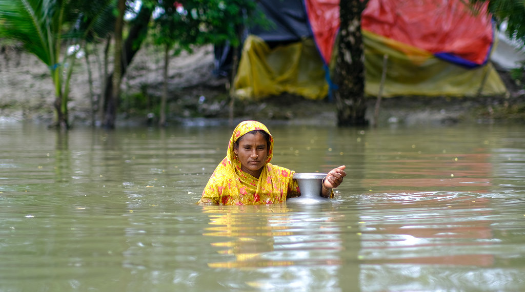 A woman wades through floodwaters in coastal Bangladesh