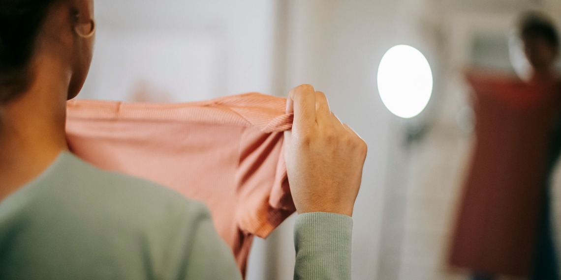 A person holds up a pink piece of clothing.
