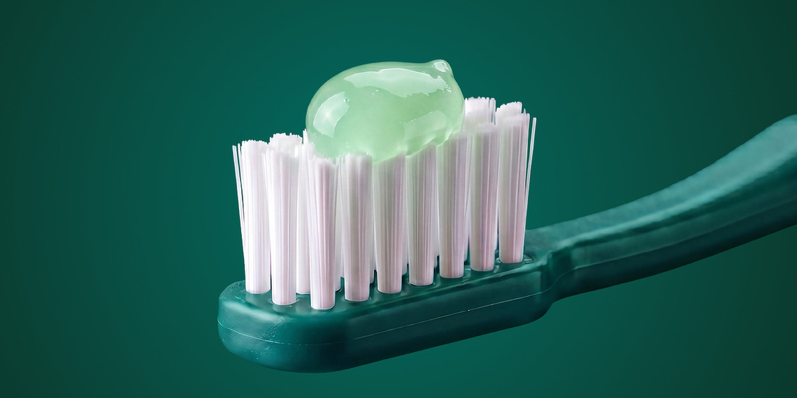 Pale green toothpaste on a green toothbrush.