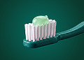 Pale green toothpaste on a green toothbrush.