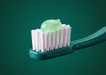 Pale green toothpaste on a green toothbrush.