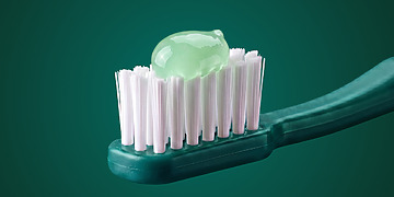 Pale green toothpaste on a green toothbrush.