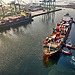 Three pilot boats push a large cargo ship into the dock.