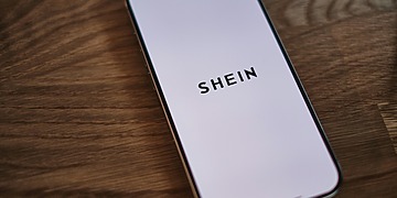 An Iphone sitting on the table with the SHEIN app open