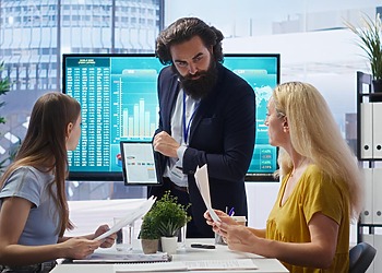 Business professional presenting accounting software to colleagues in an office
