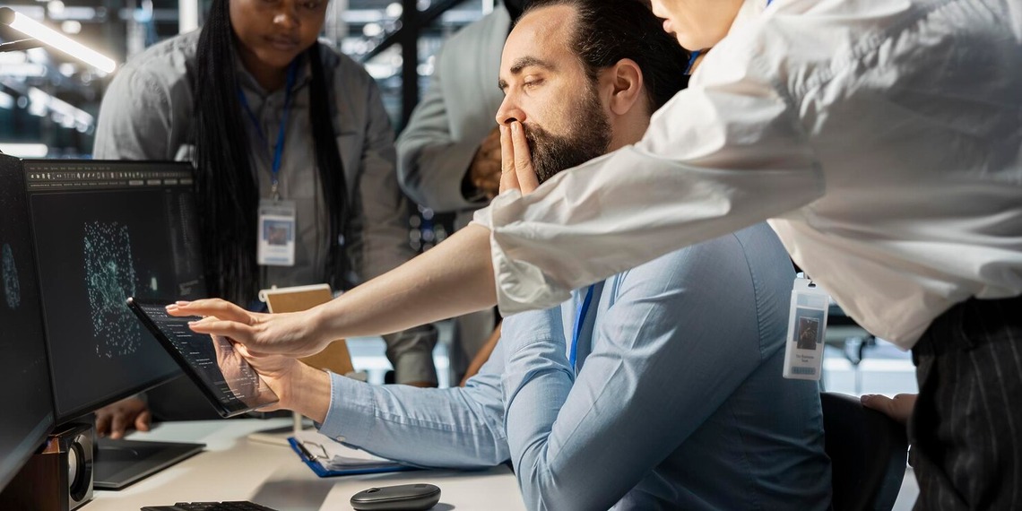Team collaborating around computer monitors in a modern office