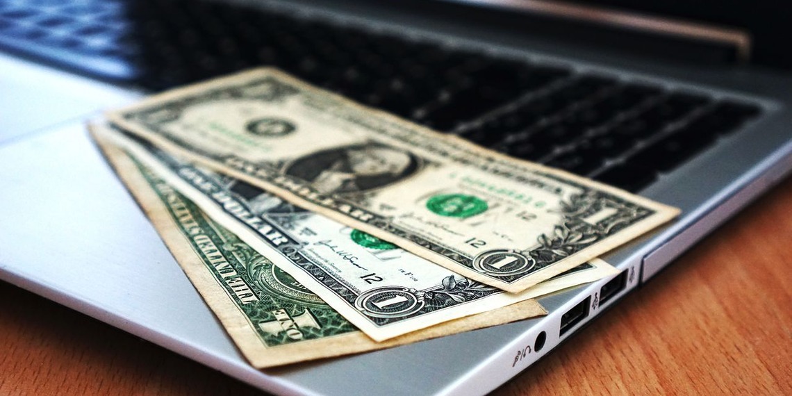US dollar bills placed on a laptop keyboard
