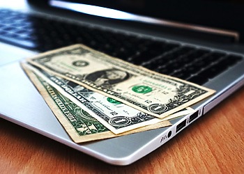 US dollar bills placed on a laptop keyboard