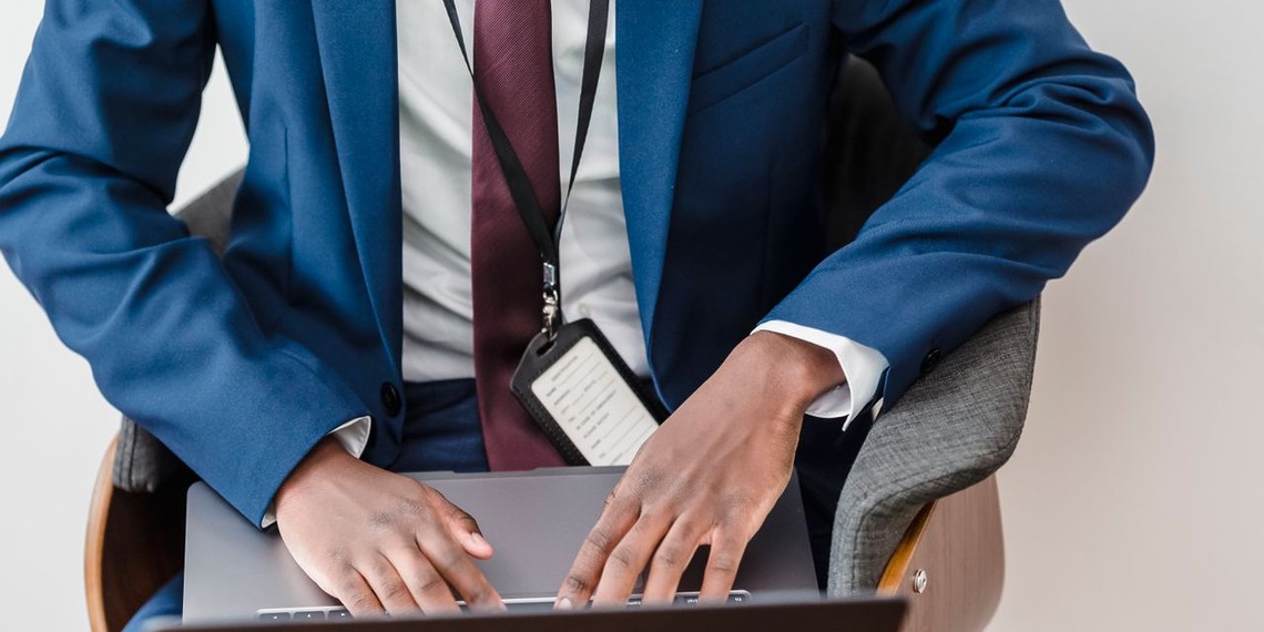 Professional using a laptop while wearing an identification badge