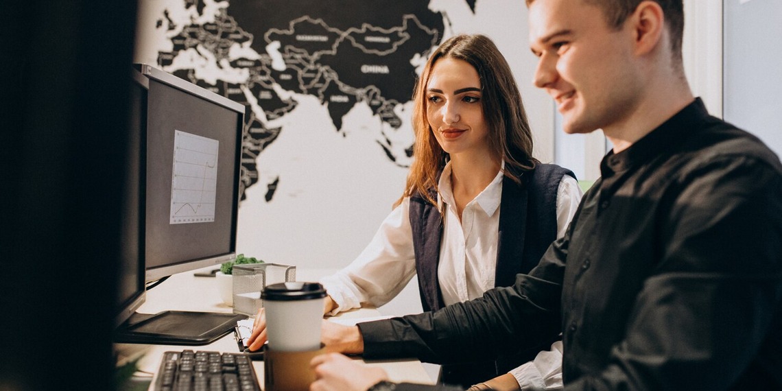 Software outsourcing professionals working at computers with a world map behind them