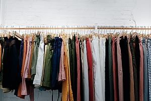 A wooden rack of assorted clothes on display