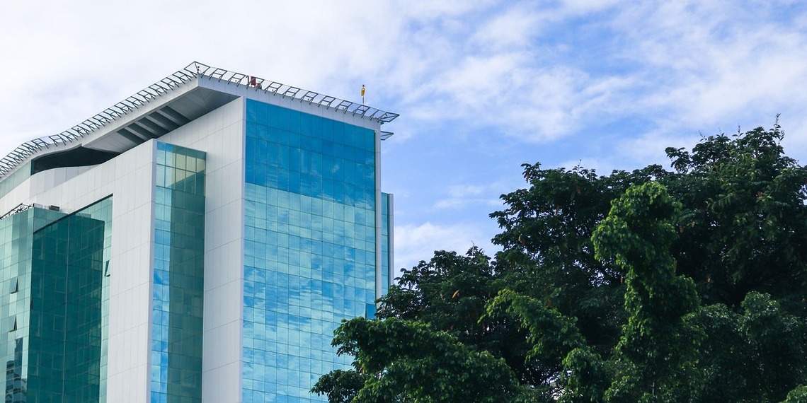 Modern glass office building surrounded by green trees