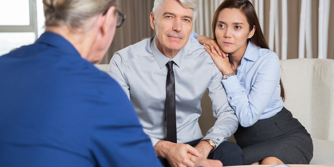 Couple seated across from a suited adviser during a private consultation