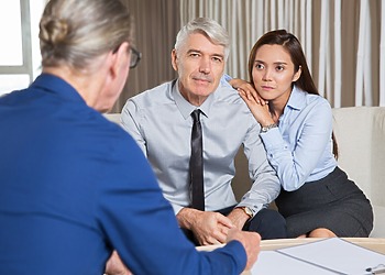 Couple seated across from a suited adviser during a private consultation